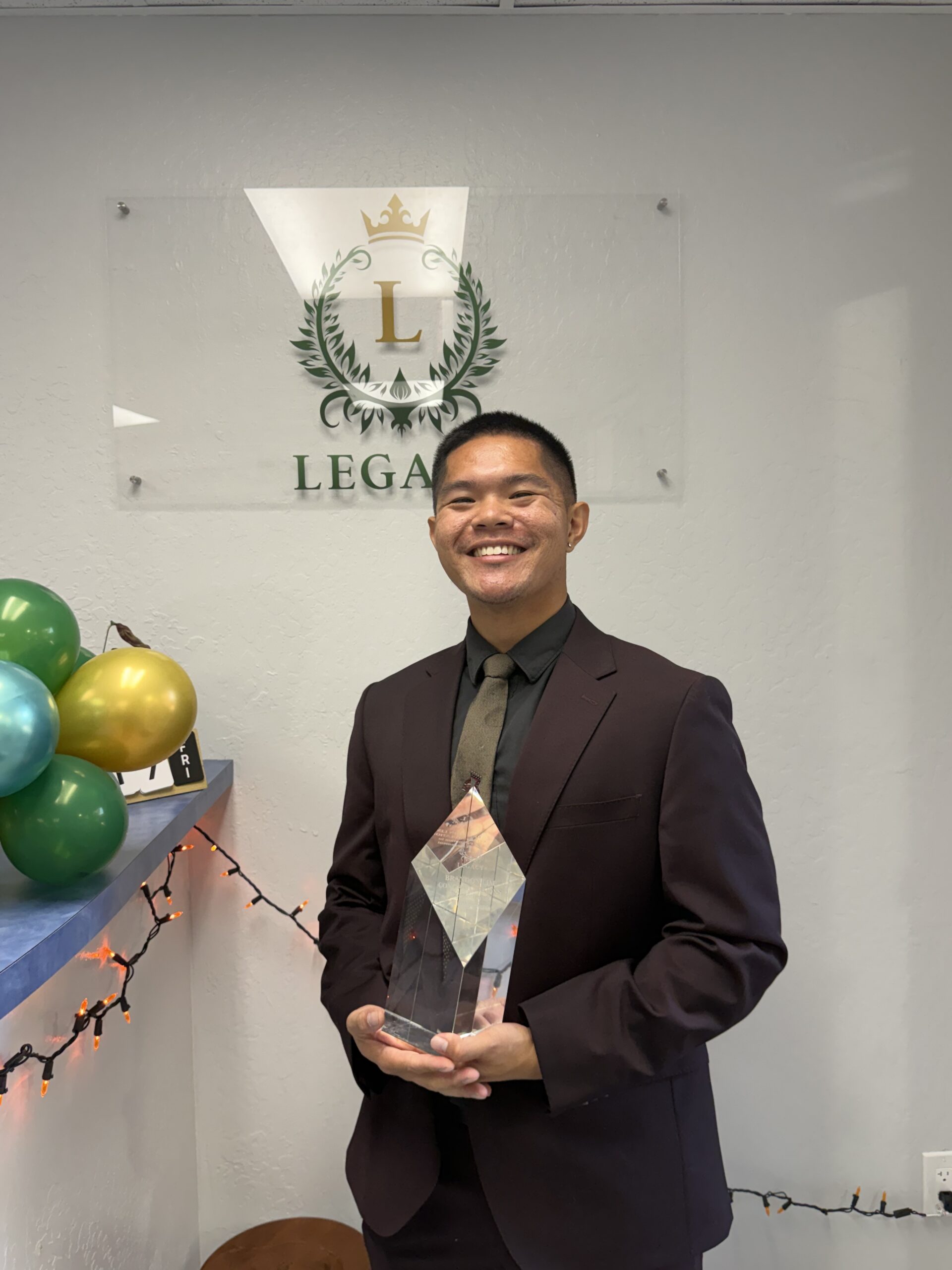 A representative from Legacy Marketing Management holding a trophy.